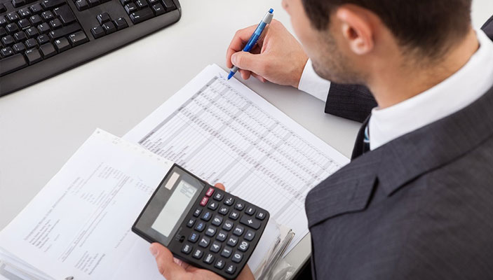 Business professional using a calculator and reviewing financial documents for debt collection