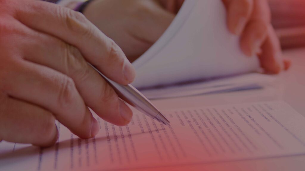 Close-up of a person reviewing and pointing at a legal document with a pen, emphasizing the importance of paperwork in debt collection or legal matters.